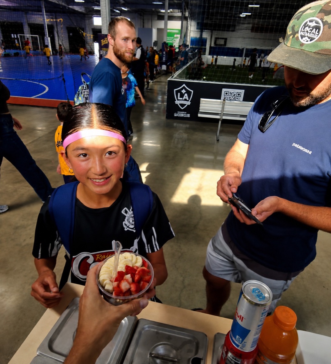 Aura Açaí catering bowl being served to a young guest at an indoor Los Angeles community event